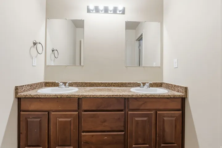 Double vanity with wood cabinetry, two undermount sinks, and a stone-finish countertop