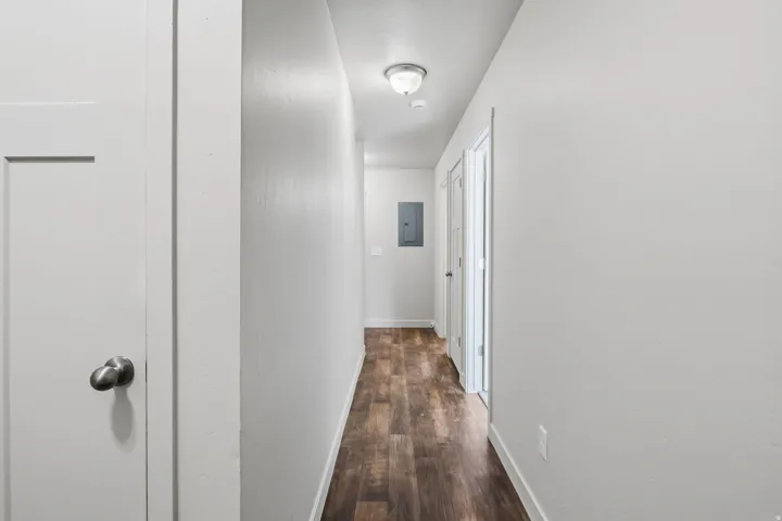Hallway featuring wood-finish flooring, light neutral paint, and white trim