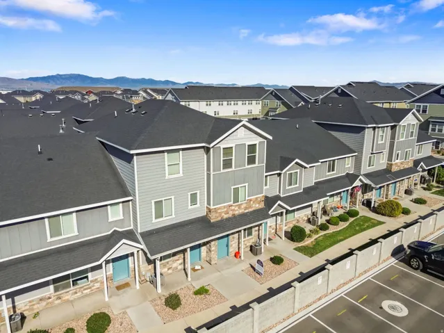 Row of townhomes featuring multi-tone siding, stone accents, covered entryways, and a structured parking area