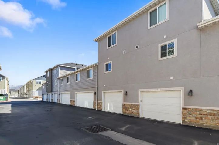 Attached garage with white door, stone veneer accent, and exterior lighting