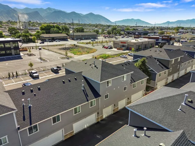 Modern townhome exteriors with attached garages, asphalt shingle roofing, and a mountainous backdrop