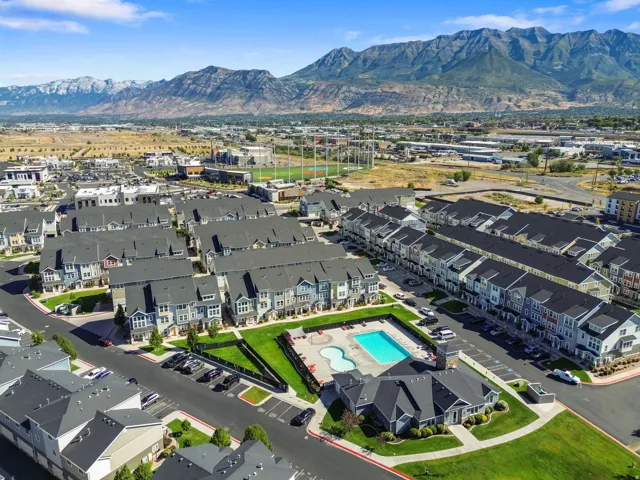 Expansive community featuring multi-story townhomes, a swimming pool, and a clubhouse, all set against a mountainous backdrop