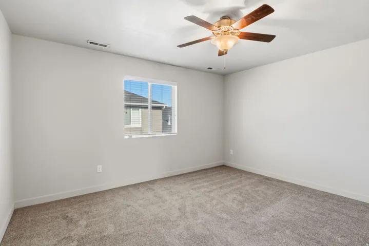 Neutral wall paint, ceiling fan with integrated lighting, window with blinds, and carpet flooring