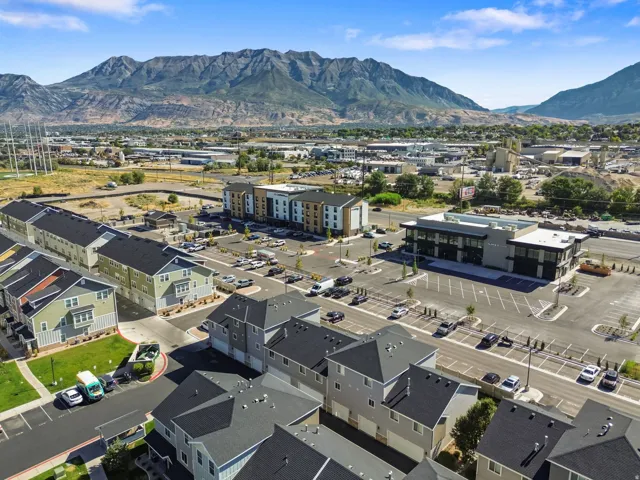 Residential community featuring multi-story townhomes and apartment buildings, with commercial structures, and mountain scenery