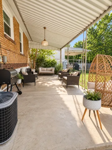 Expansive covered patio featuring a concrete surface, a ceiling-mounted light fixture, and a brick exterior wall
