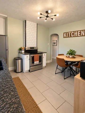 Stainless steel range, white subway tile backsplash, white cabinetry, dark speckled countertop, and light-toned tile flooring