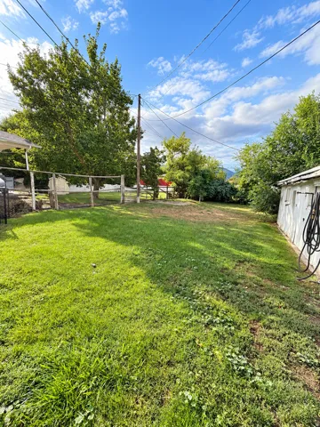 Expansive grassy yard with mature trees and a wood-post fence