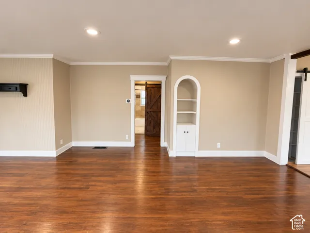 Wood-finish flooring, arched built-in shelving, recessed ceiling lighting, and a sliding barn-style door