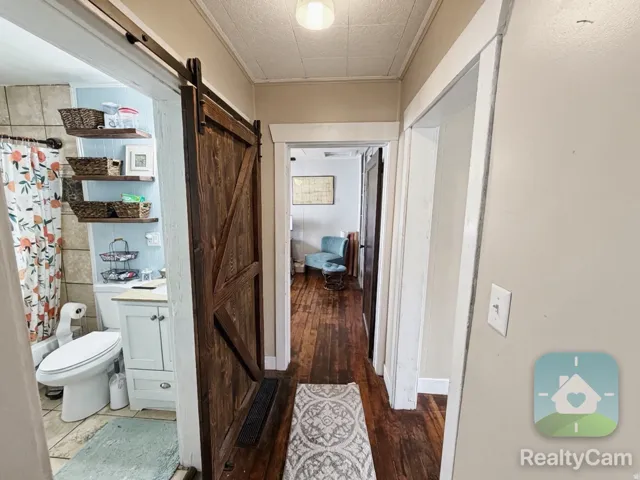 Hardwood flooring, wood-finish barn door, tile flooring, built-in shelving, white vanity with cabinet storage
