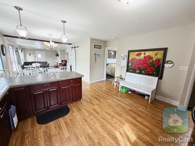 Wood-finish flooring throughout, featuring a kitchen island with dark wood cabinetry and a stone-look countertop