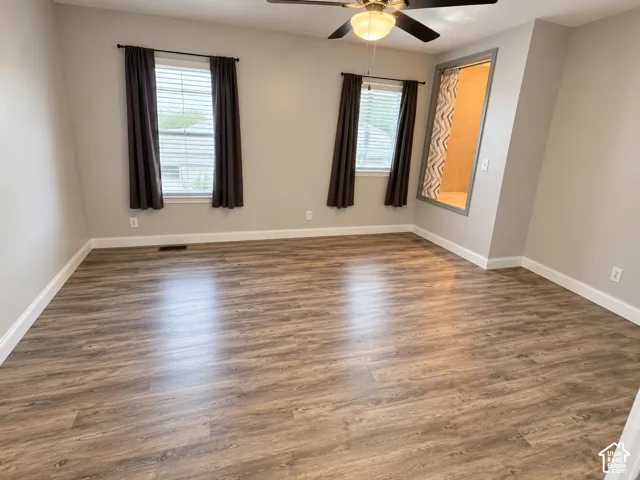 Room with wood-finish flooring, dual windows with horizontal blinds, and a built-in recessed wall niche featuring trim detail and a ceiling fan with integrated lighting