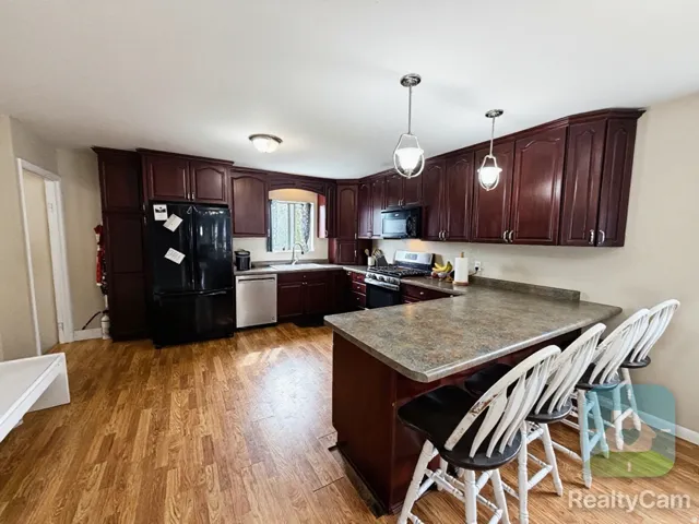 Kitchen featuring wood-finish flooring, dark wood cabinetry, a built-in kitchen island, and stainless steel appliances