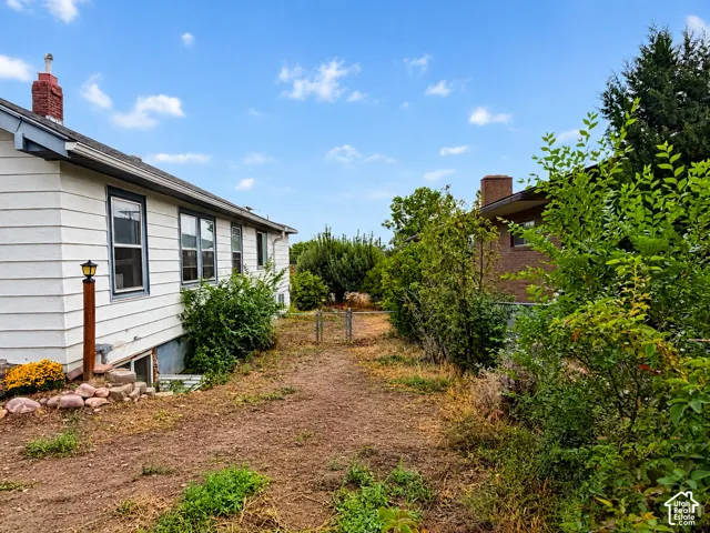 Exterior siding, chimney with brick masonry, metal-framed windows, and metal chain-link fencing
