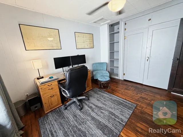 Hardwood flooring, painted paneled walls, ceiling fan, built-in shelving, and built-in closet storage
