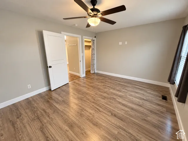 Wood-finish flooring, ceiling fan with central lighting, and interior solid-core door