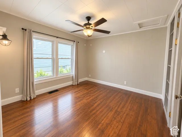 Interior space featuring wood-finish flooring, paneled wall detailing, a ceiling fan with integrated lighting, and dual-pane windows