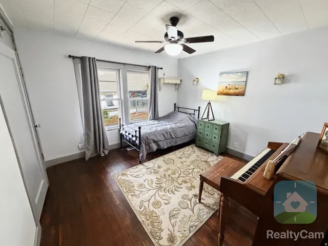 Wood-finish flooring, ceiling fan, and window with curtains