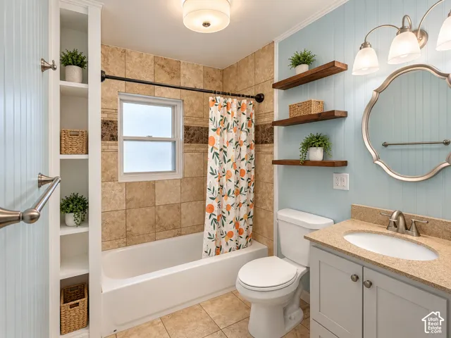 Bathroom featuring beadboard wall paneling, built-in shelving, stone-finish tile surround, wood floating shelves, and a vanity with an integrated basin