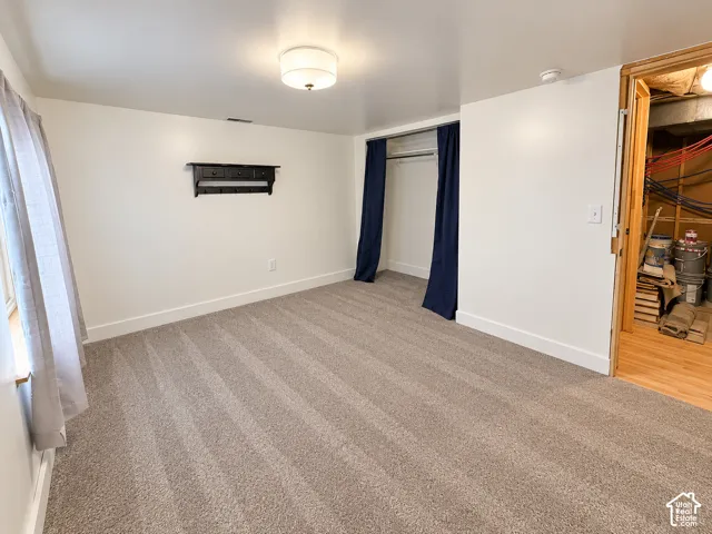 Neutral-toned wall-to-wall carpeting, recessed closet space with a metal hanging rod, and a wall-mounted wooden shelving unit featuring three small drawers