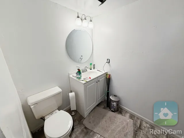 White vanity with a single sink, round mirror, and overhead light fixture
