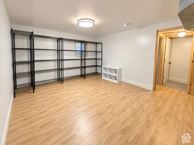 Room featuring wood-finish flooring, a flush-mount circular light fixture, and an egress window