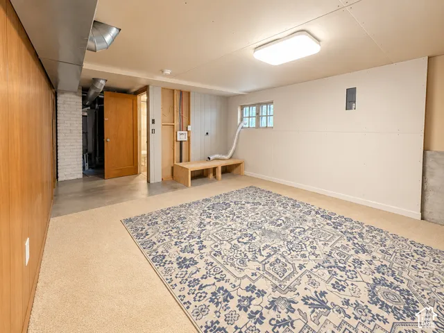 Finished lower-level room featuring wood paneling, a multi-pane window, flush-mount ceiling lighting, and a built-in wooden bench