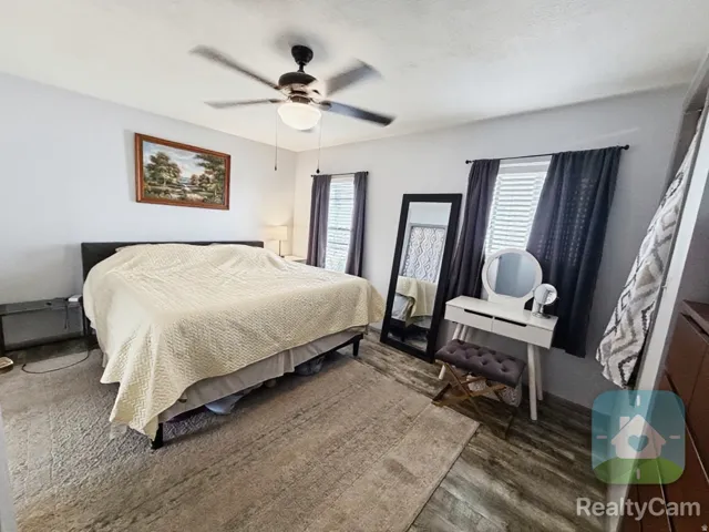 Recessed ceiling fan with integrated lighting, multiple windows with blinds and drapes, and wood-finish flooring