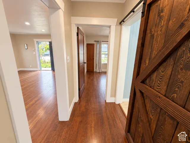 Wood-finish flooring, interior wood-tone door, sliding barn-style door with matte black hardware, and crisp white door casing
