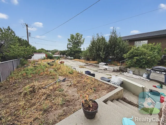 Rear exterior with concrete steps and a chain-link fence