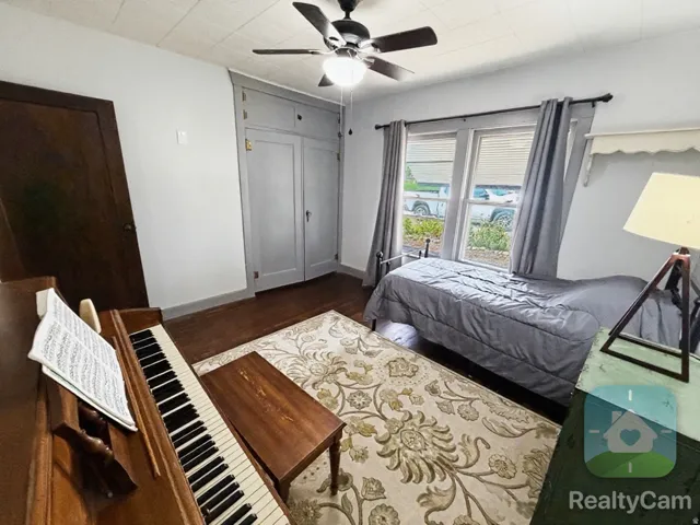 Hardwood flooring, built-in cabinetry, ceiling fan, and window with blinds