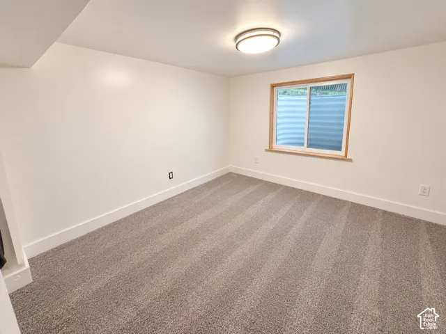 Neutral-toned interior room featuring wall-to-wall carpeting, an inset sliding window with a wood-finished frame, a built-in window well, and a flush-mount circular ceiling fixture