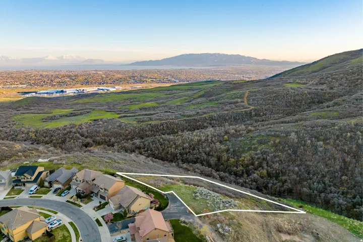 Expansive hillside lot with established neighboring properties and distant city and mountain scenery