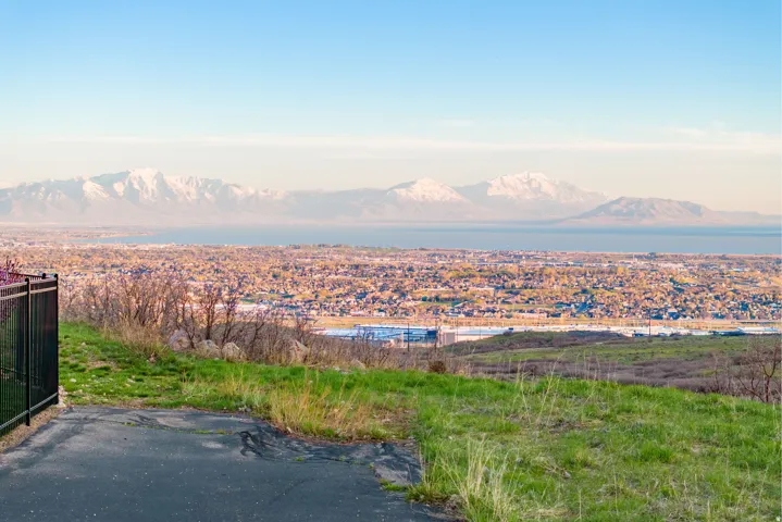 Expansive landscape featuring distant snow-capped mountains, a large body of water, and a sprawling urban area