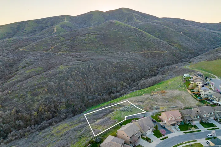 Expansive hillside lot with natural vegetation and surrounding mountain terrain