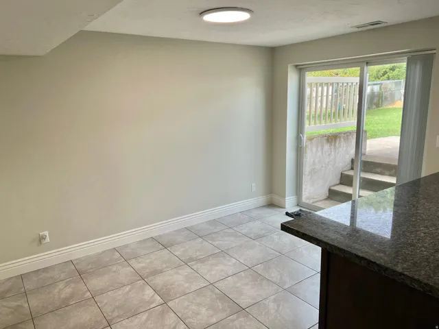 Ceramic tile flooring, sliding glass door, built-in countertop, overhead lighting, and exterior stairs to a grassy area