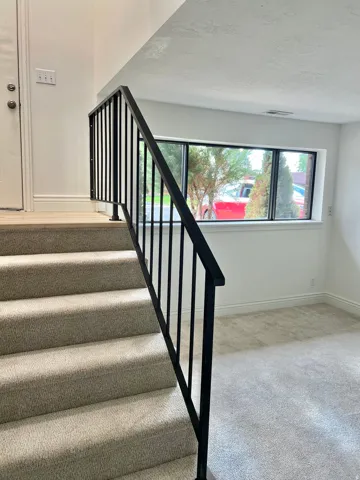 Carpeted staircase with contemporary black metal railing