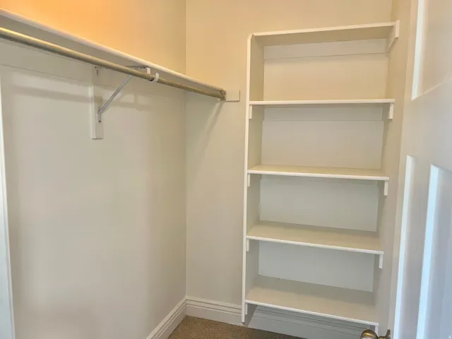 Built-in shelving and a metal hanging rod provide storage