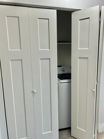 Laundry closet with white bi-fold doors and top-load washing machine