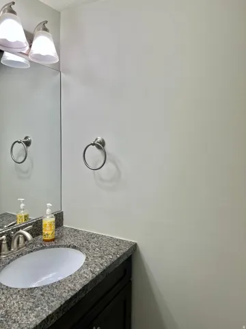 Vanity with a granite countertop, undermount sink, and brushed nickel faucet