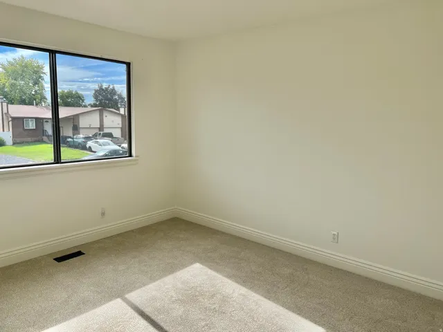Spacious room featuring neutral carpeting, light-toned wall paint, and a large window with white trim