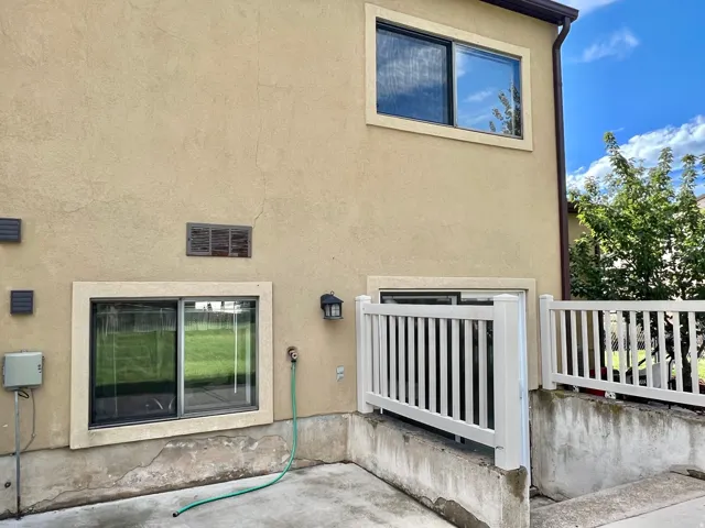 Stucco exterior with multiple windows, a sliding glass door, and white railing