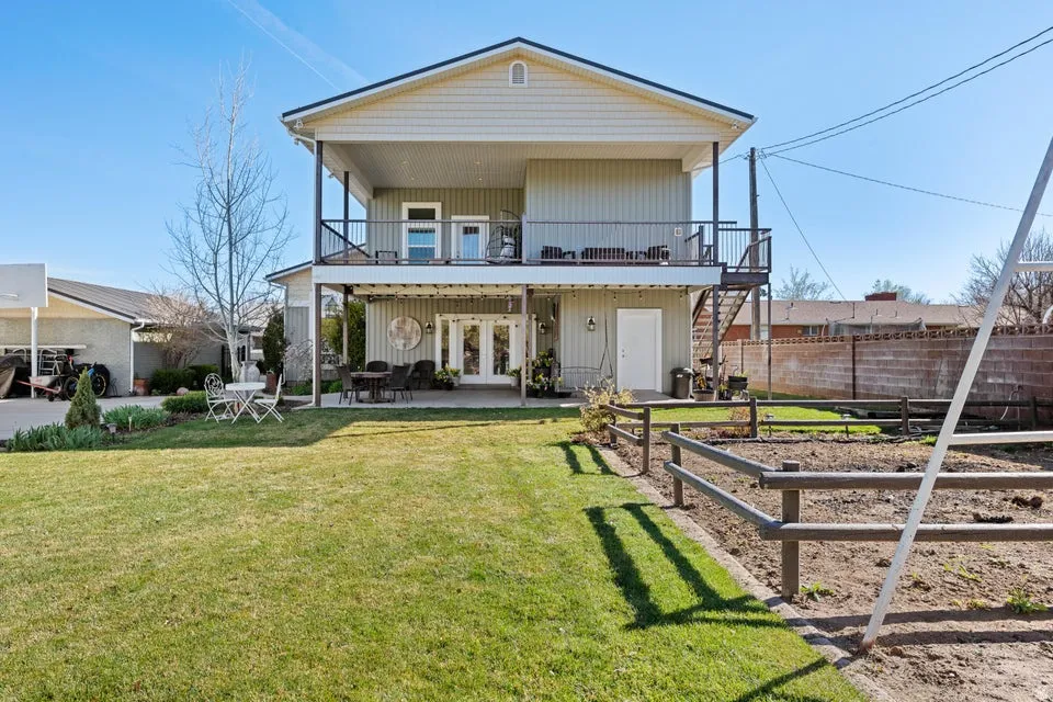 Two-story residence with a covered patio, upper-level balcony, exterior staircase, and an expansive lawn