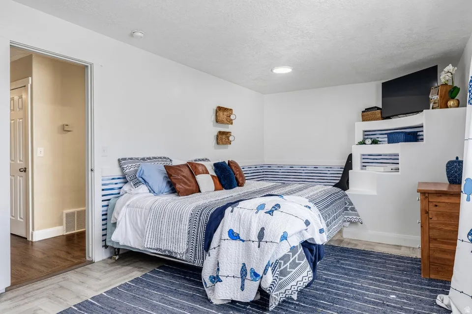 Recessed lighting, built-in shelving, wood-finish flooring, white paneled door, and neutral wall tones