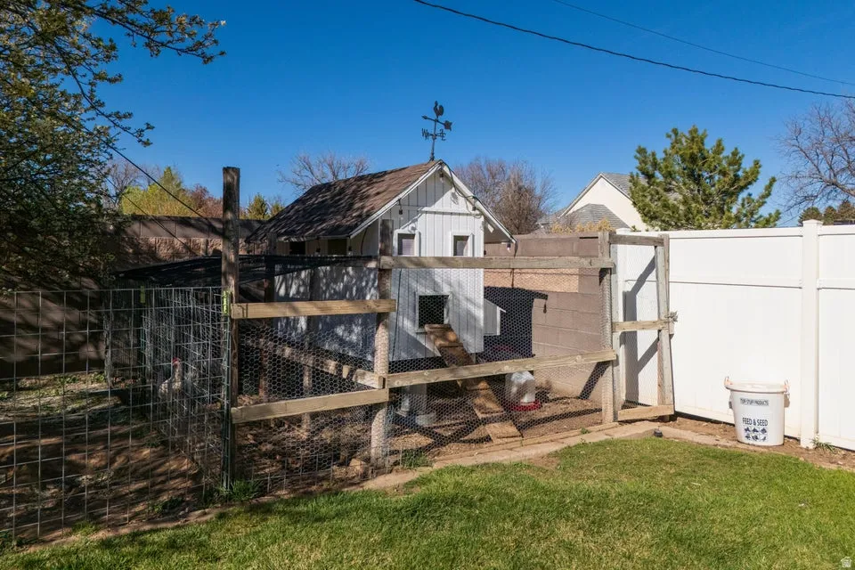 Chicken coop structure with a solid wood frame, wire mesh enclosure, and a white privacy fence