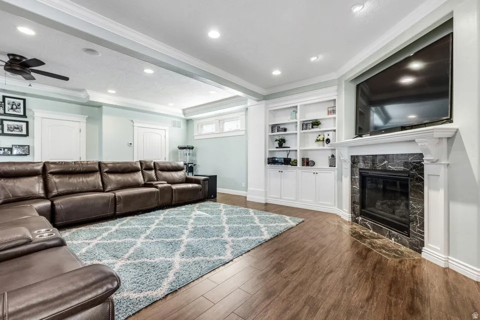Wood-finish flooring with recessed lighting, crown molding, and a ceiling fan