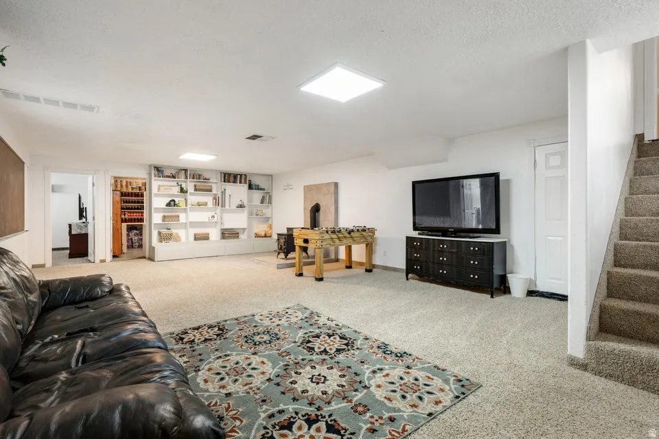Expansive carpeted area featuring built-in shelving, recessed lighting, and a neutral color palette