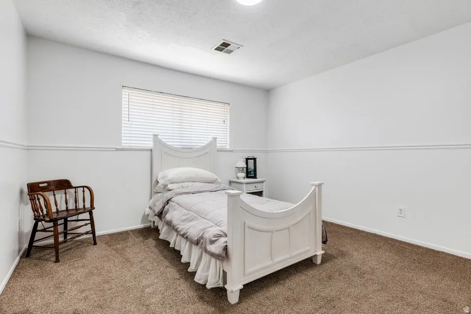 Recessed ceiling light, textured ceiling, window with horizontal blinds, neutral wall paint, and plush carpet flooring