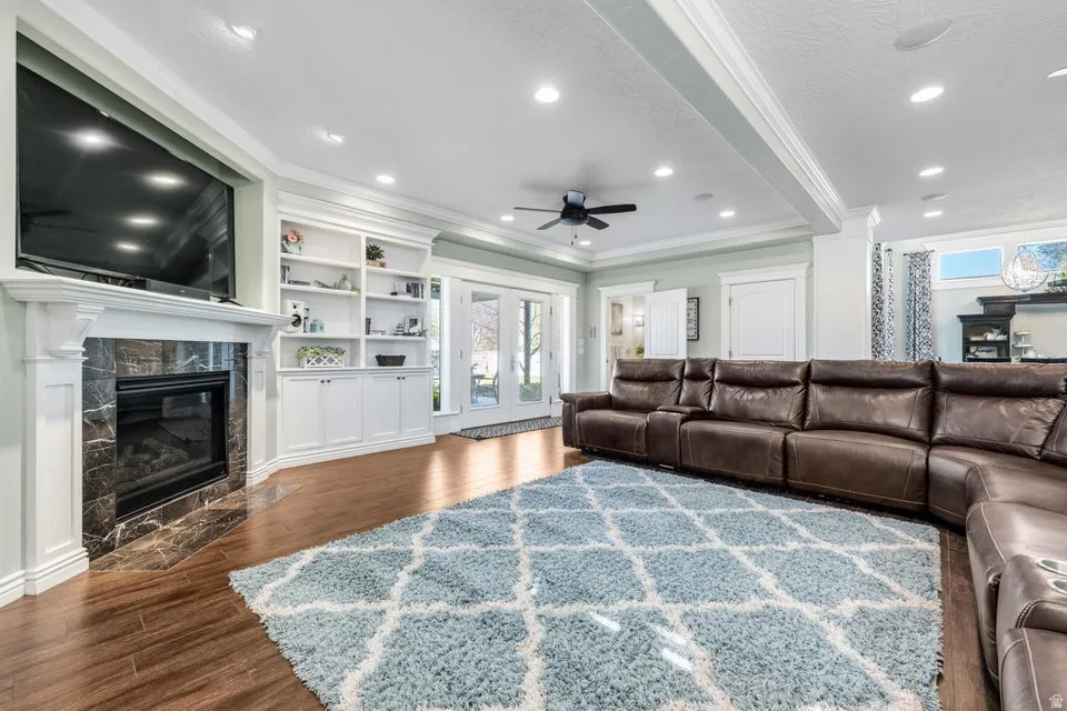Fireplace with a stone surround, built-in shelving, wood-finish flooring, recessed lighting, and French doors