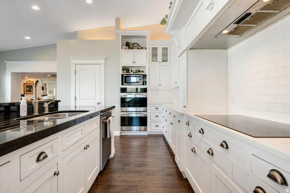 Kitchen featuring extensive white cabinetry, dark wood-finish flooring, recessed lighting, and a white subway tile backsplash