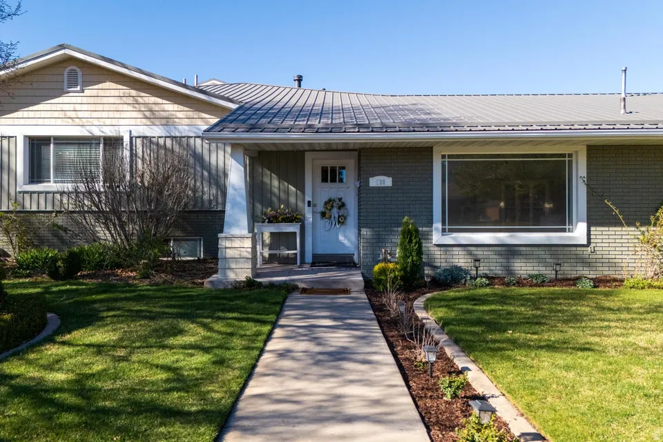 Metal roof, brick and board and batten exterior, front entry with transom window, established landscaping, and concrete walkway